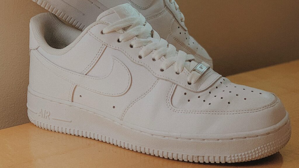 Witte sneakers van leer met perforaties en dikke zool op een houten oppervlak