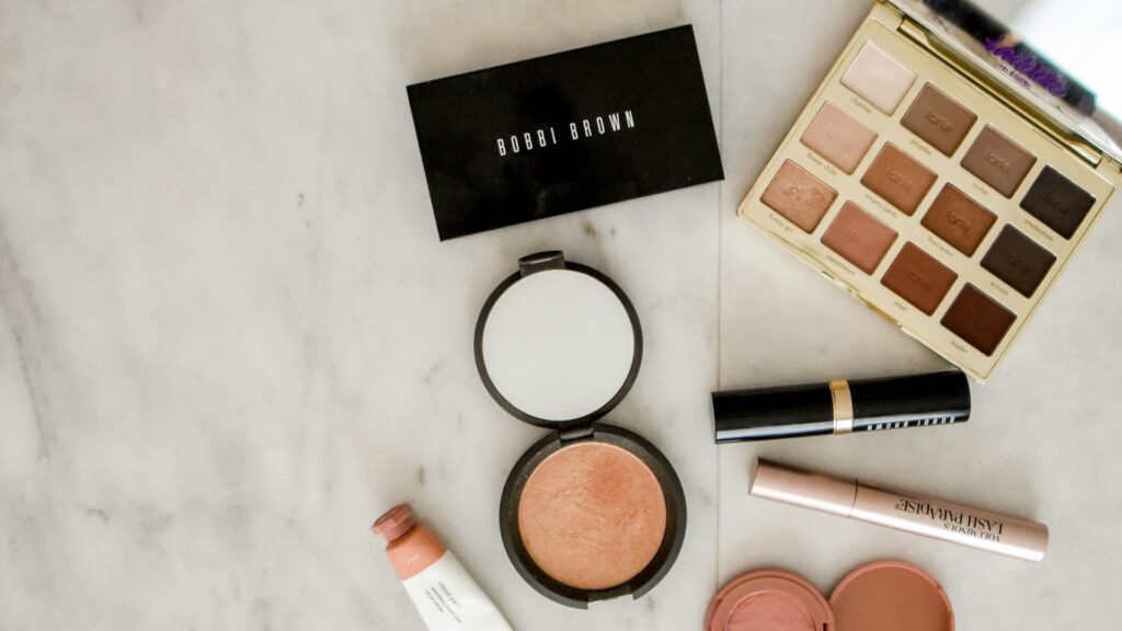Duurzame beautyproducten zoals oogschaduwpalet, blush en lipproducten op een marmeren ondergrond.